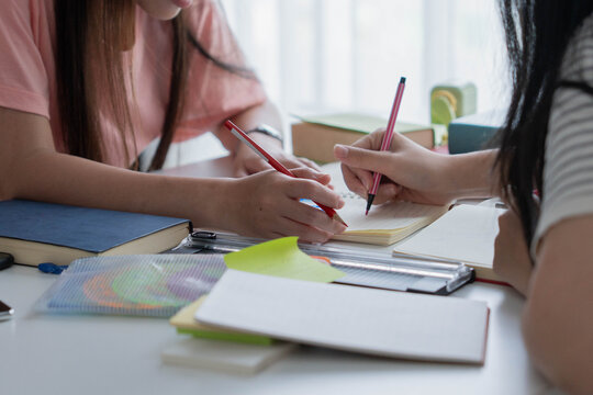 Two Asian girl with books on table doing homework together at home