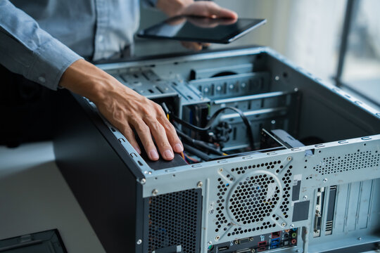 Asian IT engineer holding tablet using AI helping fix pc case