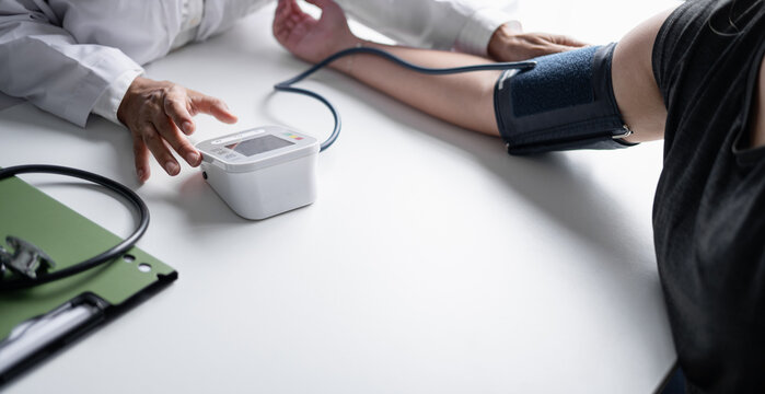 Female physician checking blood pressure of woman during routine health examination at modern medical clinic.