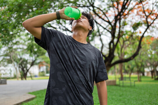 African American mixed race man drinking water after workout in urban park for healthy lifestyle