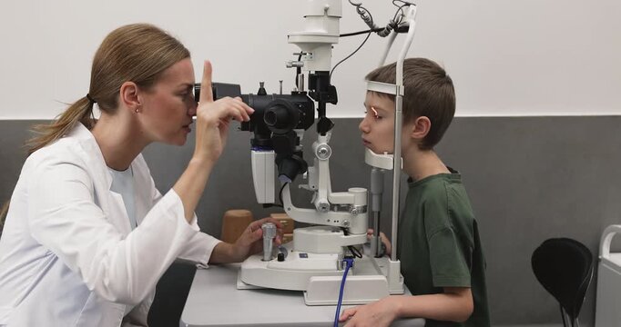 Young female pediatric ophthalmologist checking child eyesight using professional diagnostic apparatus performing eye screening for early detection of vision problems in modern clinic environment