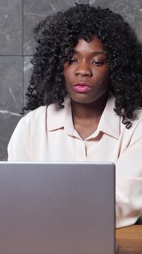 Concentrated african american businesswoman participating in a virtual meeting on her laptop, attentively listening and speaking during an important online business video conference