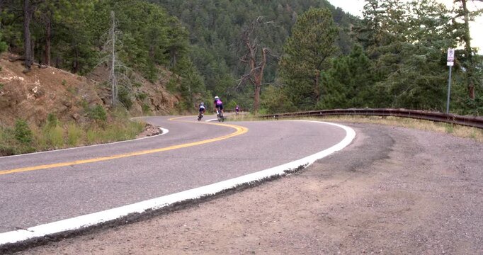 Team of cyclists quickly pass by on winding mountain road