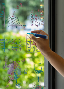 Hand writing financial data charts on glass board