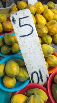 Plates of small ripe papaya pawpaw tropical fruit for sale with price sign at local fruit and vegetable market in Suva, Fiji, South Pacific