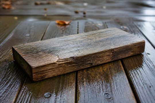 A weathered wooden block rests on wet, dark wooden planks outdoors.