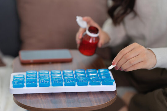 Asian woman organizing pills in a pill box for preparing daily routine medication