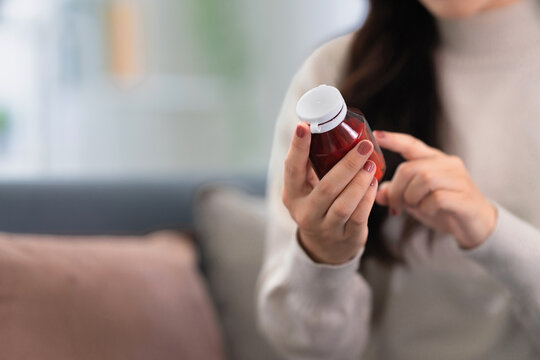 Asian woman checking on medicine bottle at home