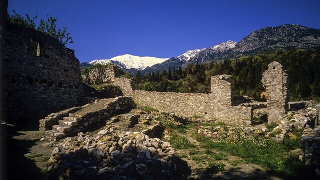Ancient stone walls of ruins against a mountain backdrop under a clear sky, Mystras, Mistra, UNESCO World Heritage Site, Medieval Byzantine ruined city, northwest of Sparta, foothills of the Tyagetos Mountains, Peloponnese, peninsula, Greece