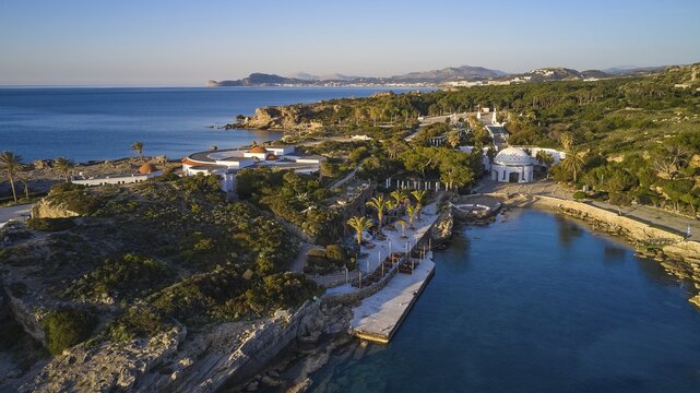 Drone shot, morning light, A coastline with palm trees and buildings, surrounded by the blue sea, with a forest in the background. Mediterranean atmosphere, Kalithea, Kallithea, thermal baths, spa, Rhodes, Dodecanese, Greek Islands, Greece