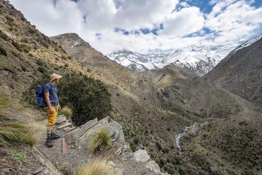 Hiker on a hiking trail, hiking trail Vereda de la Estrella, behind Sierra Nevada with summits Mulhac&eacute;n and Pico Alcazaba, snow-covered mountains near Granada, Andalusia, Spain