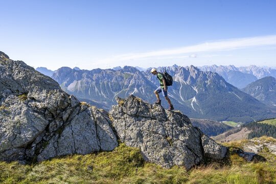 Mountaineer on a rocky ridge in front of a mountain panorama, view of the mountain peaks of Cresta Righile and Cresta del Ferro in South Tyrol, Carnic High Mountain Trail, Carnic Main Ridge, Carnic Alps, Carinthia, Austria