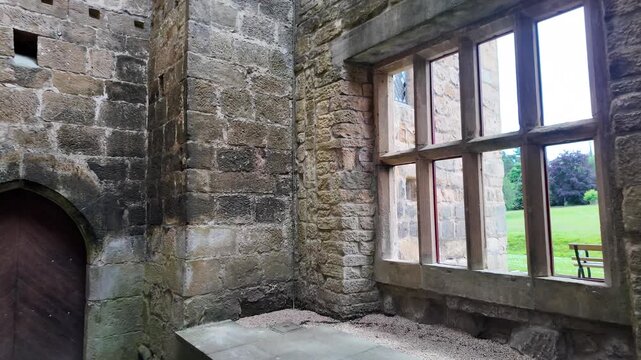 Historical abandoned stone castle interior showing a large window and the green park outside