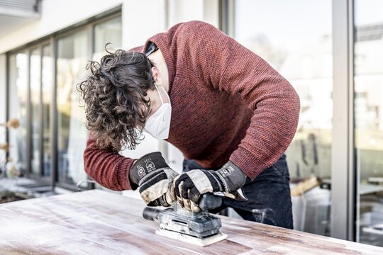 Young man doing DIY, grinding table with a grinder