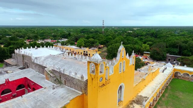 Aerial view of the yellow church facade of the San Antonio convent in Izamal, Yucatan, Mexico, ochre walls decorated with red festival banners.
