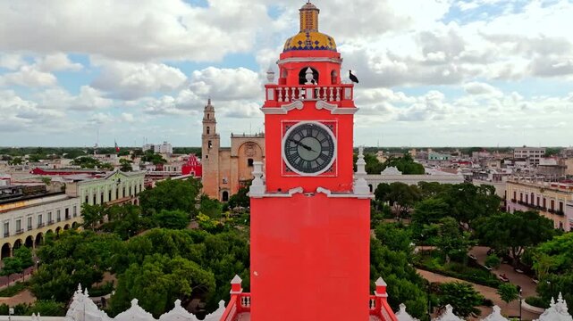 Aerial view of a red colonial building and clock tower in central Merida, Yucatan, Mexico, the colonial capital spreading out beyond it.