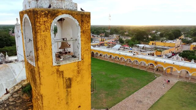 Aerial view of a corner of the great yellow arcade and atrium of the San Antonio convent in Izamal, Yucatan, Mexico, arches lining the green court.