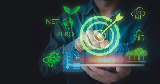 Businessman touching target icon on tablet for Net Zero carbon emissions concept. Sustainable development goals, green technology, renewable wind energy, AI innovation, and environment policy.