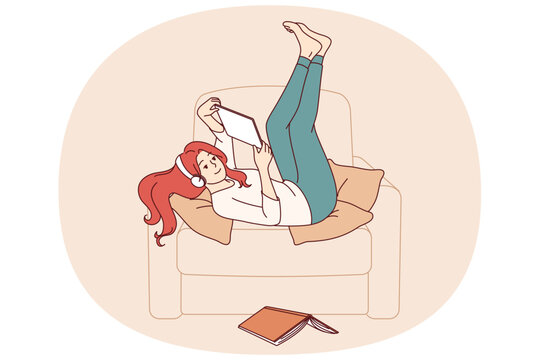 Lazy girl student listens to music lying in chair, distracted from reading textbook to prepare for exams. Lazy young woman enjoying using gadgets, doing idleness after hard day at work.