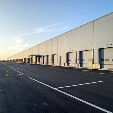 Vast modern industrial warehouse with multiple loading docks under a clear sky