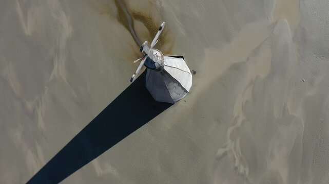 Aerial slow motion view of a church tower with cross, buried under mud in decanting lake