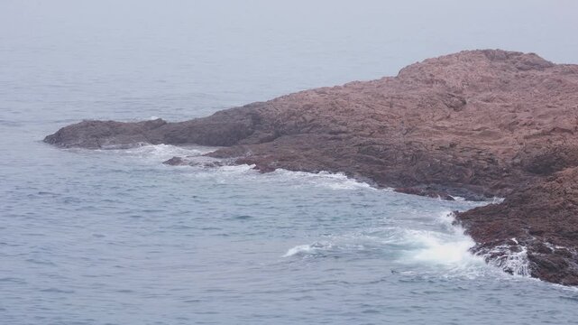 Gentle ocean waves rippling around a rocky tidal shore background video
