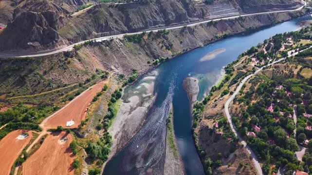 Smooth cinematic forward flight follows a flowing river while the camera gradually tilts upward, revealing a wider landscape, tranquil water, and an immersive natural perspective.