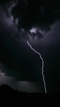 A massive bolt of lightning illuminates a stormy night sky with a dark storm cloud looming overhead.