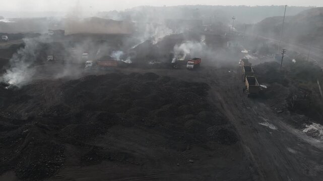Open Pit Coal Mine with Smoke and Haul Roads, Aerial View of Active Coal Mining Site, Industrial Mining Landscape with Heavy Equipment, Drone Shot of Coal Stockpiles and Mine Operations stock video.
