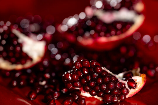 Ripe red pomegranates arils with scattered seeds. Pomegranate arils on red plate. Pomegranate seeds. Red ruby pomegranate arils.