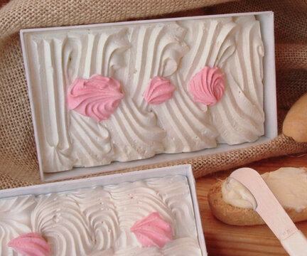 Mantequilla artesanal de Soria con denominaci&oacute;n de origen Espa&ntilde;a decorada con detalles de merengue rosa en caja blanca sobre mesa r&uacute;stica