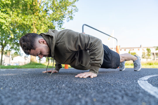 Young man performing pushup exercise outdoors for fitness workout