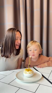 Woman and toddler blowing out candle on birthday cake