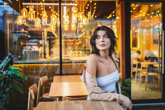 Portrait of a young woman in a cafe with warm bokeh lighting