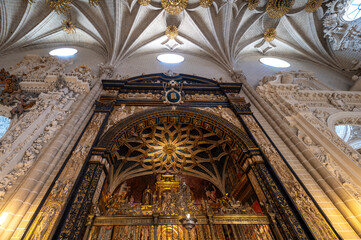 Fototapeta premium Low angle vertical view of the Parish Chapel (Capilla de la Parroquia or San Miguel) entrance, featuring a star-patterned mudéjar vault, ornate iron grille, dark marble archway, and gothic ribbed vaul