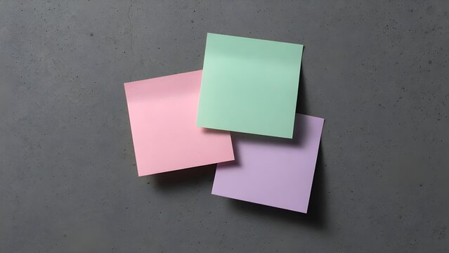 Three colorful blank sticky notes on a grey concrete background
