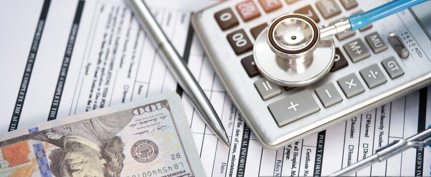 Medical expenses and budgeting. Stethoscope rests on calculator. Paperwork and cash show financial strain. Silver pen points to cost details. Image speaks of healthcare costs