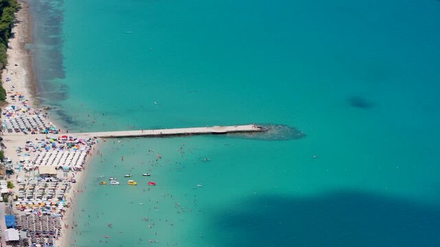 Aerial view of crowded beach with pier and turquoise sea