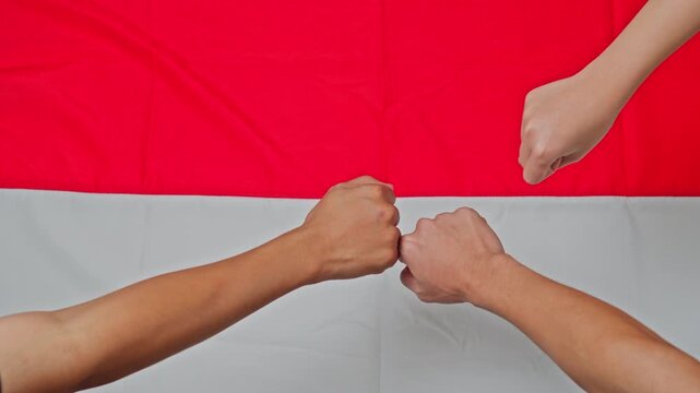 Multiple fists bumping together over red and white Indonesian flag background
