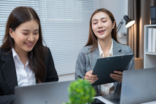  Two professional women work together at a desk, reviewing information on a laptop, collaborating on teamwork and business planning, and analyzing data.