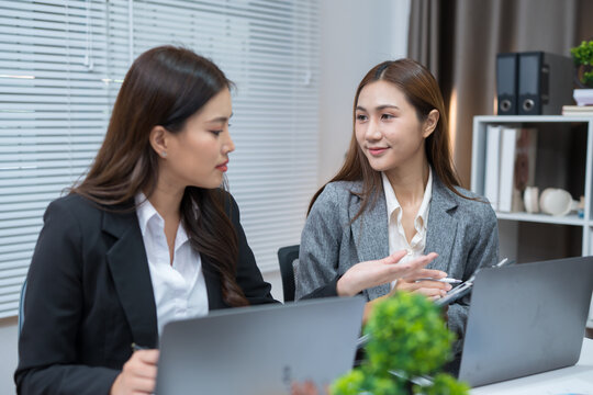 Two professional women work together at a desk, reviewing information on a laptop, collaborating on teamwork and business planning, and analyzing data.