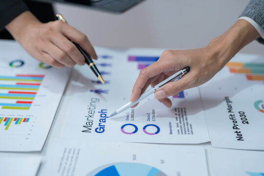  Two professional women work together at a desk, reviewing information on a laptop, collaborating on teamwork and business planning, and analyzing data.