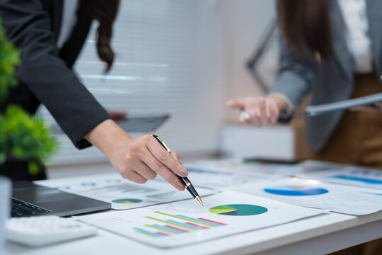  Two professional women work together at a desk, reviewing information on a laptop, collaborating on teamwork and business planning, and analyzing data.