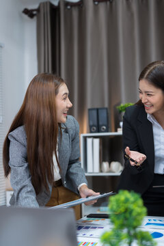  Two professional women work together at a desk, reviewing information on a laptop, collaborating on teamwork and business planning, and analyzing data.