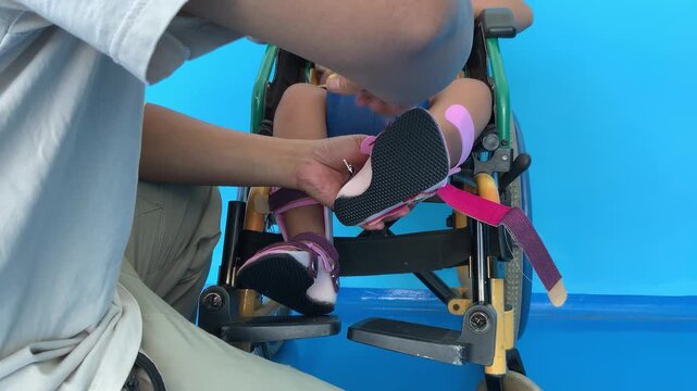 A father helping his young son put on shoes over an ankle-foot orthosis (AFO) brace.