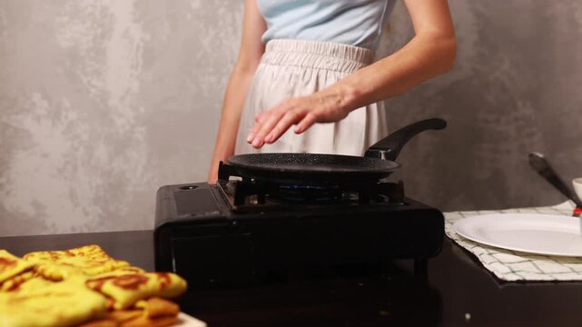 A woman toasts pancakes with stuffing in a frying pan in the kitchen