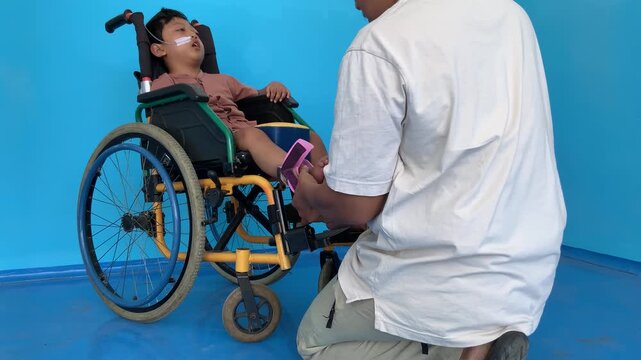 A father helping his young son put on shoes over an ankle-foot orthosis (AFO) brace.