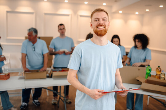 Young man volunteering with clipboard smiling at camera