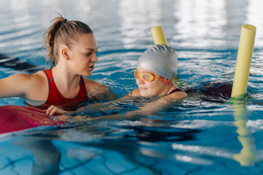 Instructor teaching young girl swimming in pool