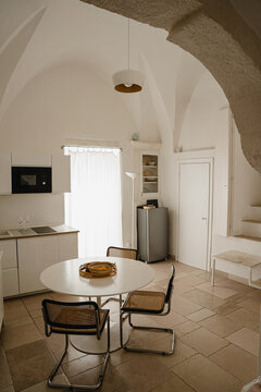 Sunlit Dining Area With White Table Vintage Cane Chairs And Fruit Bowl